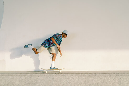 Ethnic skater riding skateboard on border