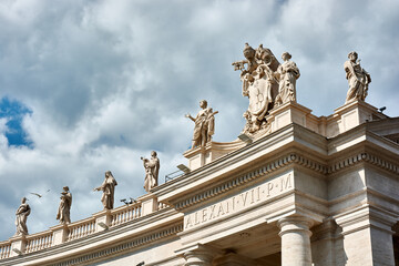 Fototapeta na wymiar A view of sculptures on top of the Tuscan Colonnades and blue cloudy sky at St. Peter's Square in the Vatican city in Rome, Italy.