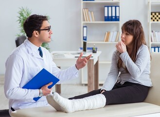 Fototapeta premium Doctor examining patient with broken leg