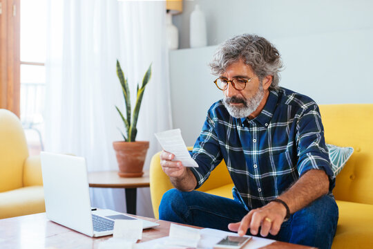 Aged man checking bills at home office
