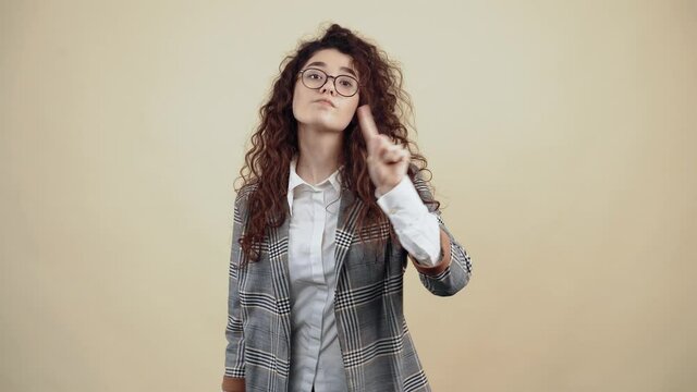 The indisposed teacher, with her index finger in front, denies the accusations saying no Cretaceous in gray jacket and white shirt, with glasses posing isolated on a beige background in the studio