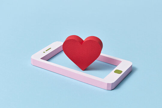 Handcraft paper smartphone with red heart symbol.