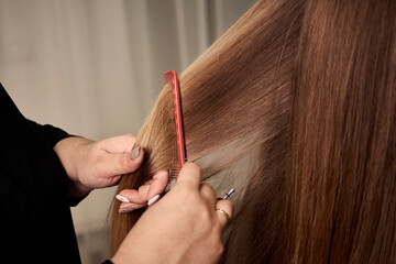 Close-up of a woman combing her blonde hair with a comb. Beauty salon. Professional hair care.