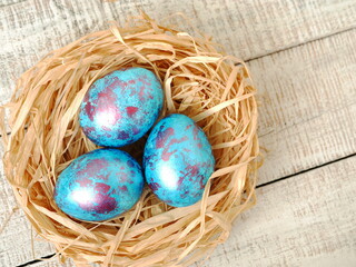 Easter flatlay with beautiful painted eggs in the nest. Concept of Easter egg hunt or egg decorating art.