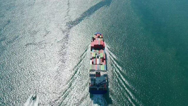 Aerial view of a small and a huge merchant vessels sailing across the Atlantic. Multicolored container vessel transports the goods as seen from the top. High quality 4k footage