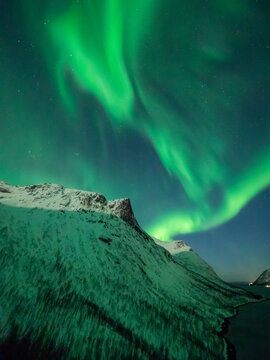 Strong northern lights over snow covered mountains in Norway.