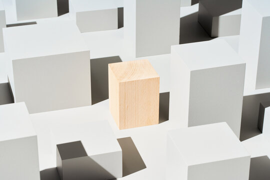 Wooden cube amidst geometric shapes