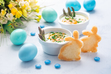 Shirred eggs (Oeuf cocotte) or baked eggs with green asparagus with Easter bunny and eggs