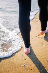 Joven mujer paseando por la orilla del Mediterráneo mojando sus pies en el mar. 