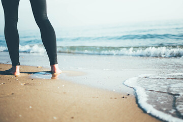 Joven mujer paseando por la orilla del Mediterráneo mojando sus pies en el mar. 