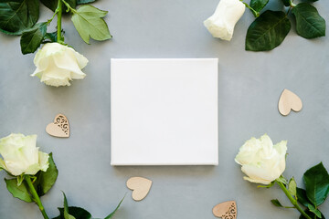 Romantic message, congratulation, valentine's day concept. Blank canvas and white roses. Top view. Mockup poster.