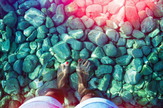 My feet in clear water on stony beach in Cephalonia
