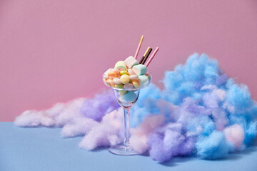 A glass of Iced strawberry shake and topped with cotton candy and marshmallow