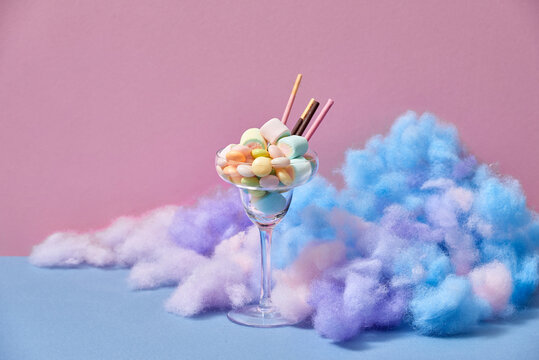 A glass of Iced strawberry shake and topped with cotton candy and marshmallow