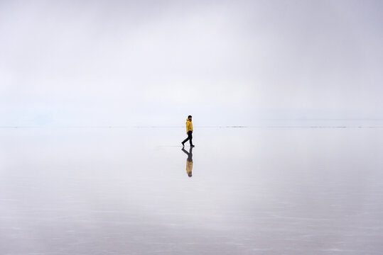 Reflection of a man walking in Uyuni's salt flat in Bolivia
