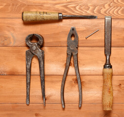 top view on wooden background old often used hand tools screwdriver and nippers, pliers and chisel.
