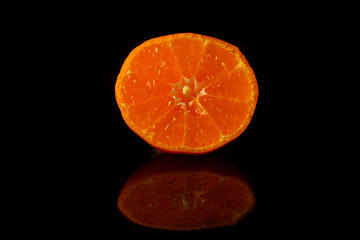 Slice of fresh tangerine isolated on black background