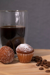 coffee in a double bottom glass near two little cupcakes. coffee break. breakfast