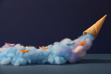 Origami paper boats on cotton candy are poured from a waffle horn