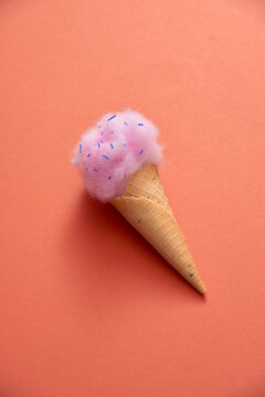 Ice cream cone with fluffy cotton candy on color background