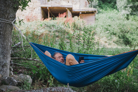 man rests in hammock reading an electronic book