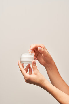 Anonymous female taking cream from jar