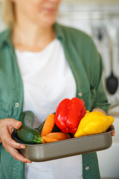 Crop woman carrying tray with vegetables
