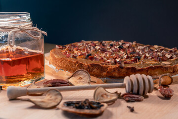 Still life with homemade organic food. Pear pie, jar with honey and dipper, cinnamon, dried fruits, nuts. Healthy breakfast without added sugar.