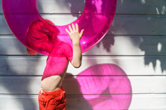 Boy Holding Pink Innertube in Summer Sunshine