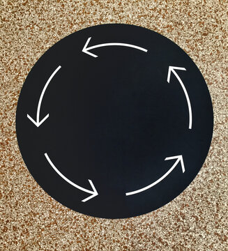 black circle with white arrows on stone floor