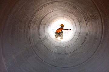 Construction worker inspecting water pipeline. India.