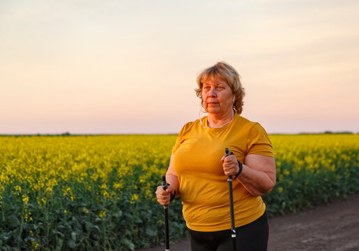 Mature woman listening to music and walking with sticks