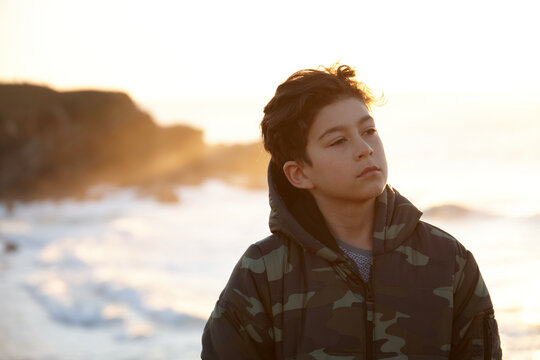 Young boy thinking and looking out over the ocean