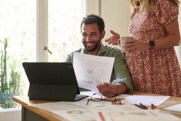 Cheerful man reading data and listening to female colleague