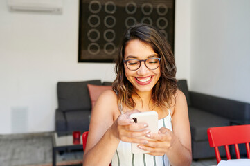 Smiling businesswoman using her cellphone at home