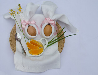 Beautiful festive Easter brunch with eggs in  napkin bunny, oranges and flowers on a basket.