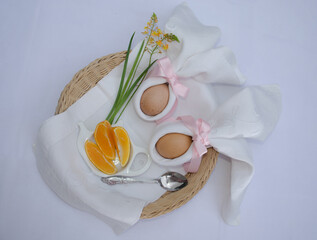 Beautiful festive Easter brunch with eggs in  napkin bunny, oranges and flowers on a basket.