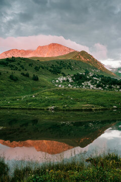 Mountain range with the sinset reflected in the cloud of the peak and its reflection in the lake