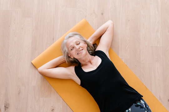 Relaxed elderly sportswoman resting on floor