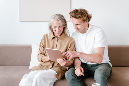 Cheerful grandmother and grandson using tablet together