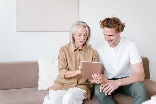 Cheerful grandmother and grandson using tablet together