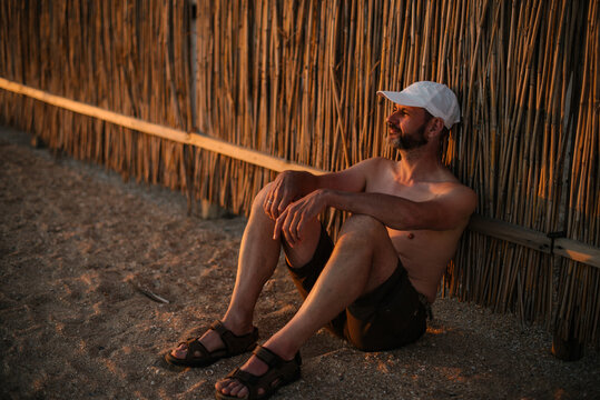 Portrait of an adult man with a beard sitting in the rays of the setting sun