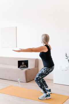 Unrecognizable senior woman squatting during online training