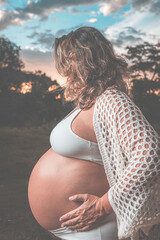 pregnant woman from the side with white clothes and a wonderful sky in the background
