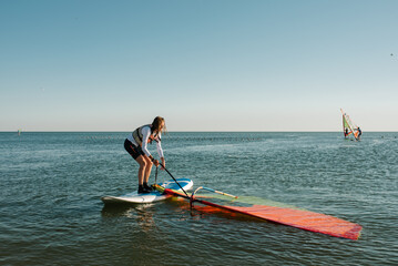 A girl learn to sail on a windsurf on the summer day