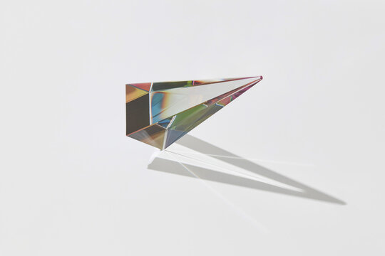 Flying colorful glass pyramid with long shadows.