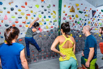 Modern friends with instructor practicing climbing wall