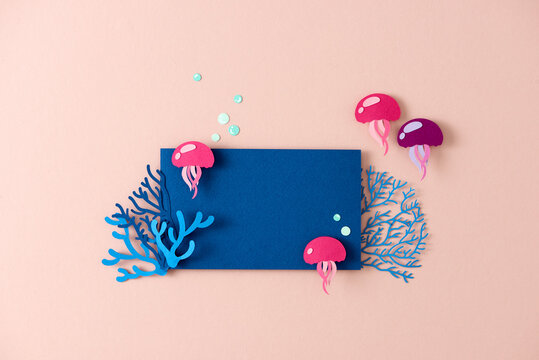 Coral reef copy space frame template with colorful papercut jellyfish on pink background.