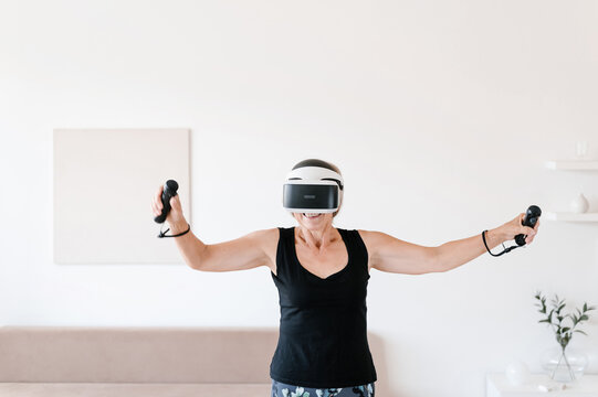Senior sportswoman doing dumbbells exercise in VR
