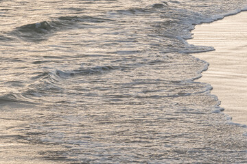 ocean waves reaching the shore at sunset..